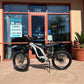 Silver Dirt Bike Surron Light Bee X LBX in front of a retail store Hyper Rides